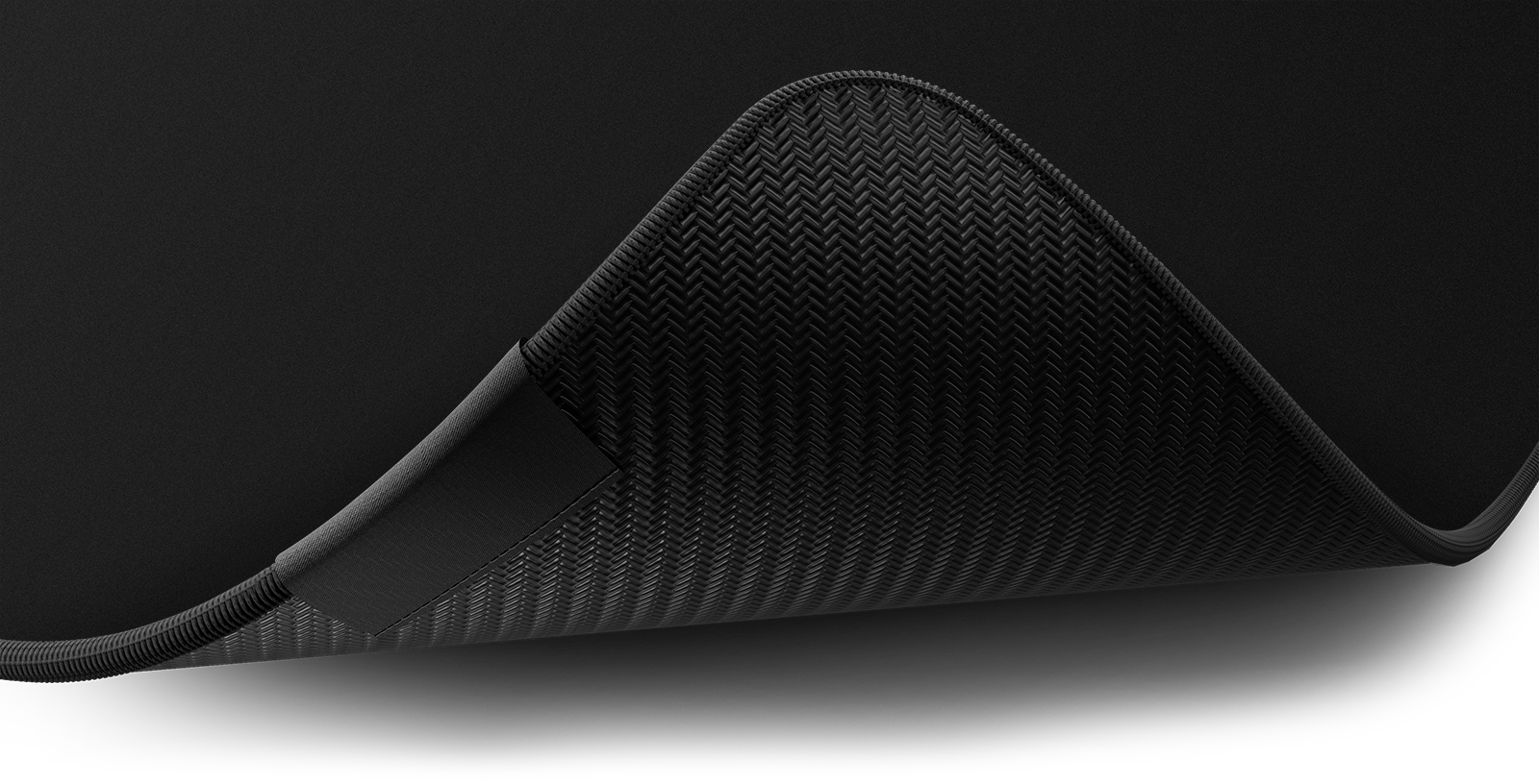 Close-up of the stitched edge and non-slip rubber base of the Hystar Classic deskmat in Black. Black XXL (36" x 16"), Black XXXL (45" x 20")