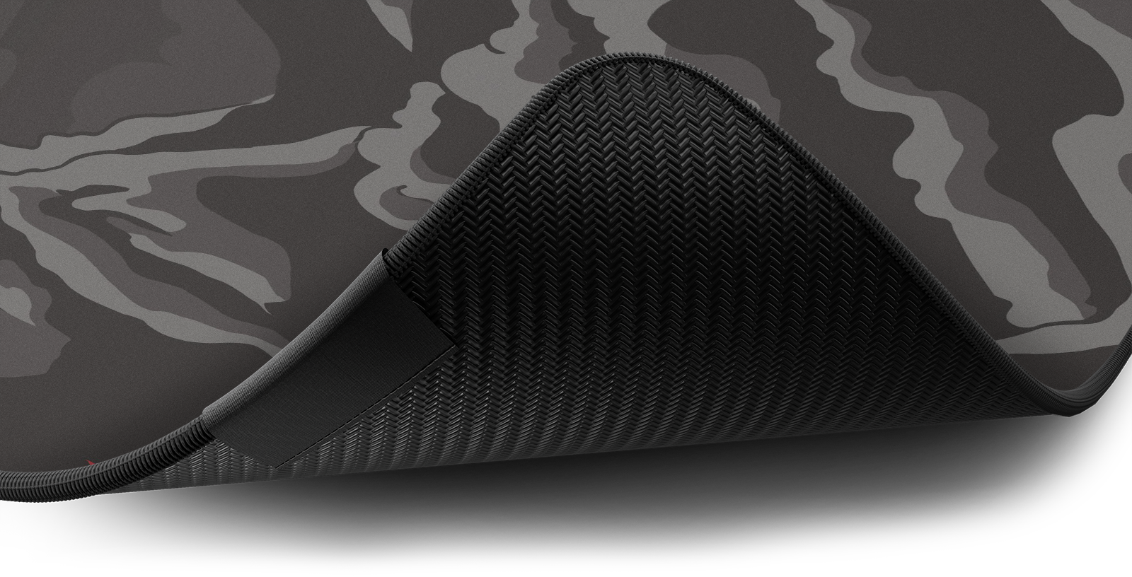Close-up of the stitched edge and non-slip rubber base of the Hystar Drift deskmat